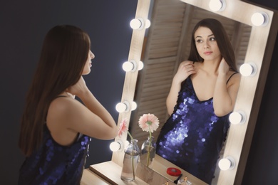 Young beautiful woman looking in mirror