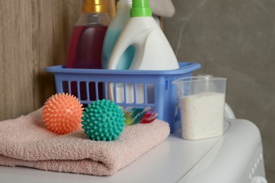Photo of Dryer balls, detergents and clean towel on washing machine