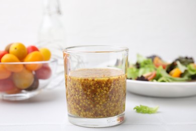 Tasty vinegar based sauce (Vinaigrette) in glass on light table, closeup