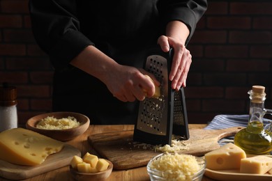 Photo of Woman grating cheese at wooden table, closeup