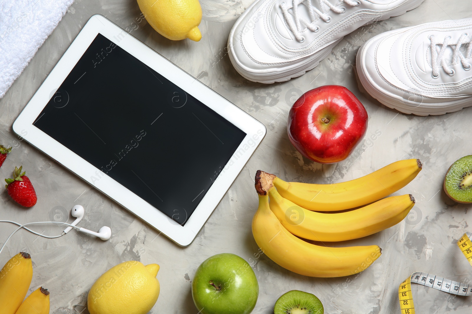 Photo of Flat lay composition with sneakers, healthy food, tablet and space for text on grey background. Weight loss concept