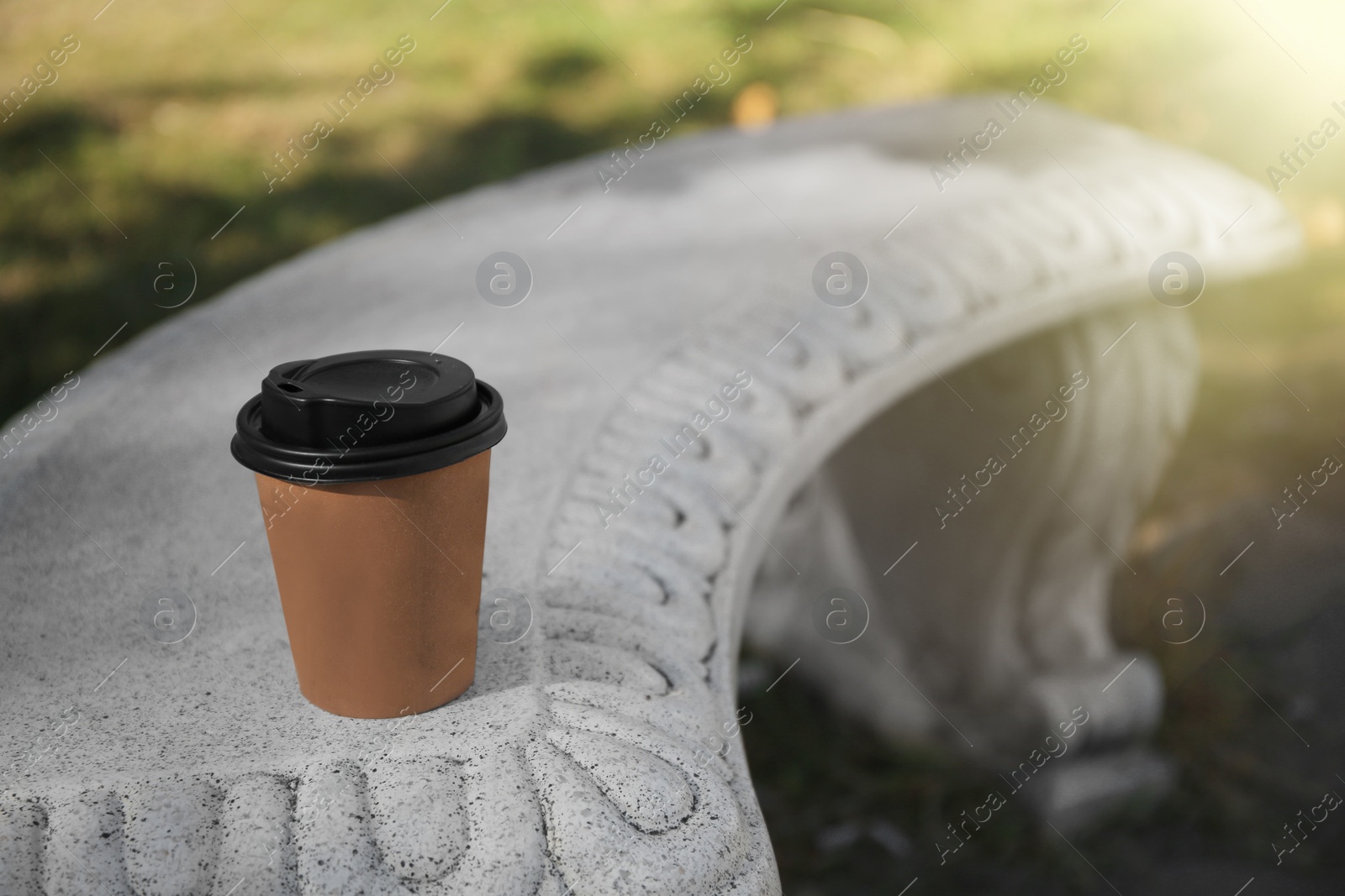 Photo of Cardboard cup with tasty coffee on stone bench outdoors. Space for text