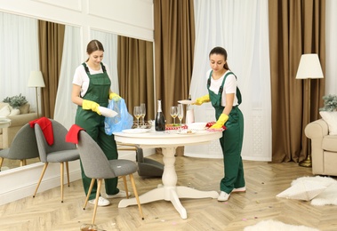 Photo of Cleaning service team working in messy room after New Year party