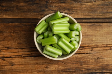 Photo of Cut celery in bowl on wooden table, top view