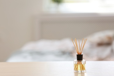 Photo of Aromatic reed air freshener on table against blurred background