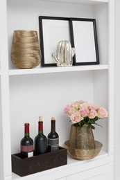 Shelves with different decor and rose flowers indoors. Interior design