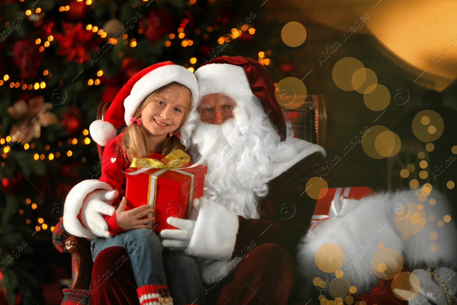 Photo of Santa Claus and little girl with gift near Christmas tree indoors