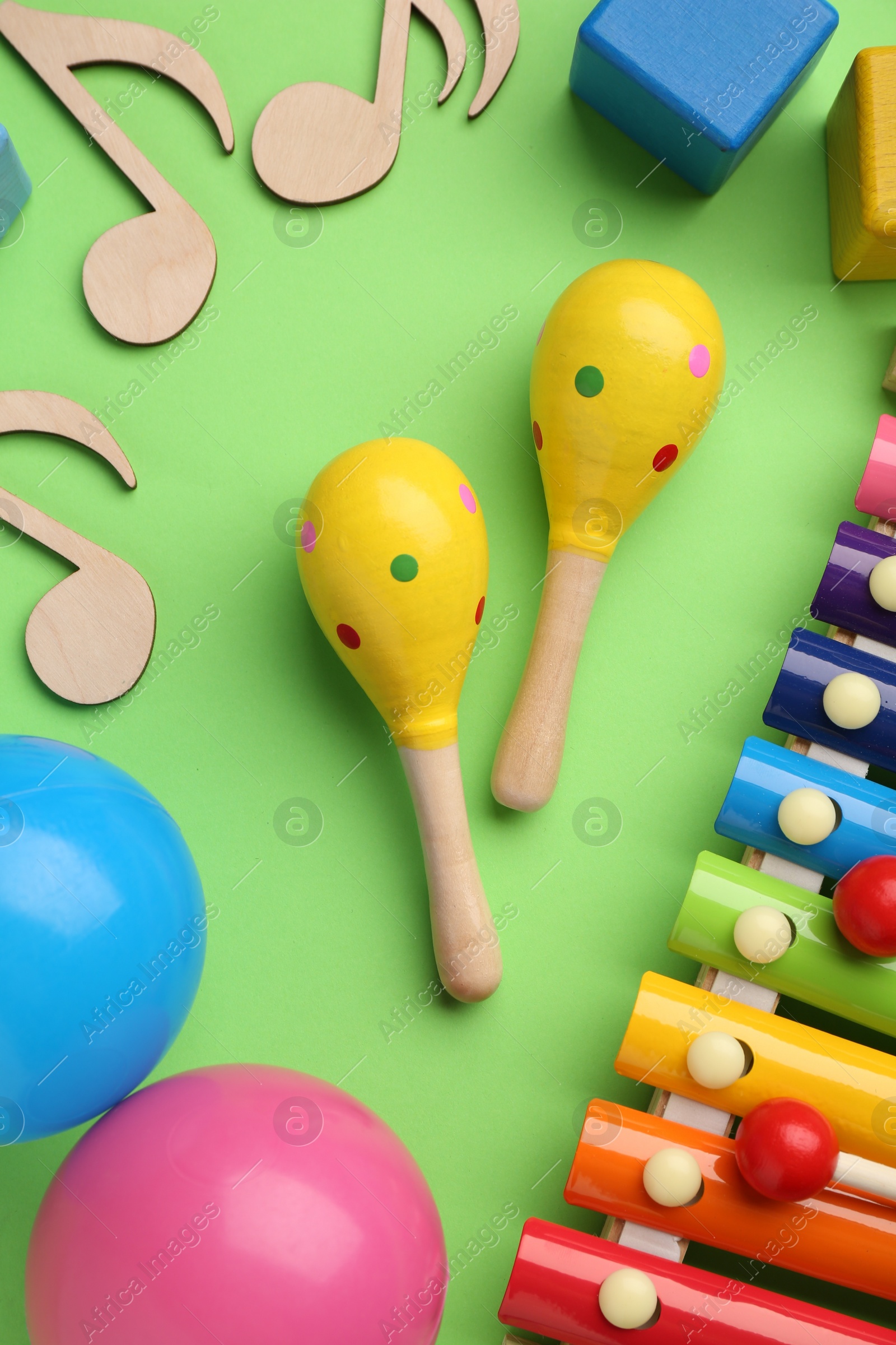 Photo of Tools for creating baby songs. Flat lay composition with maracas on green background