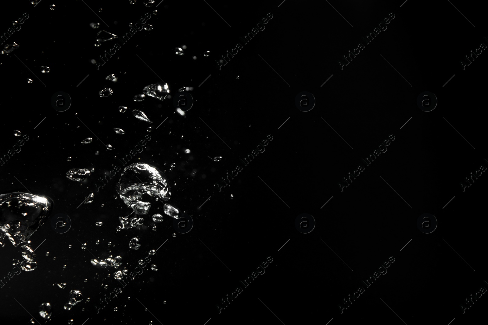 Photo of Air bubbles in water on black background, space for text