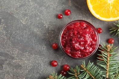 Flat lay composition with bowl of cranberry sauce and space for text on grey background