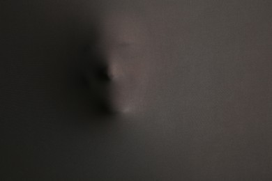 Photo of Silhouette of creepy ghost with skull behind grey cloth. Space for text