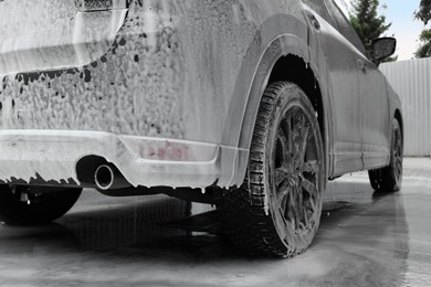 Auto with cleaning foam at car wash, closeup