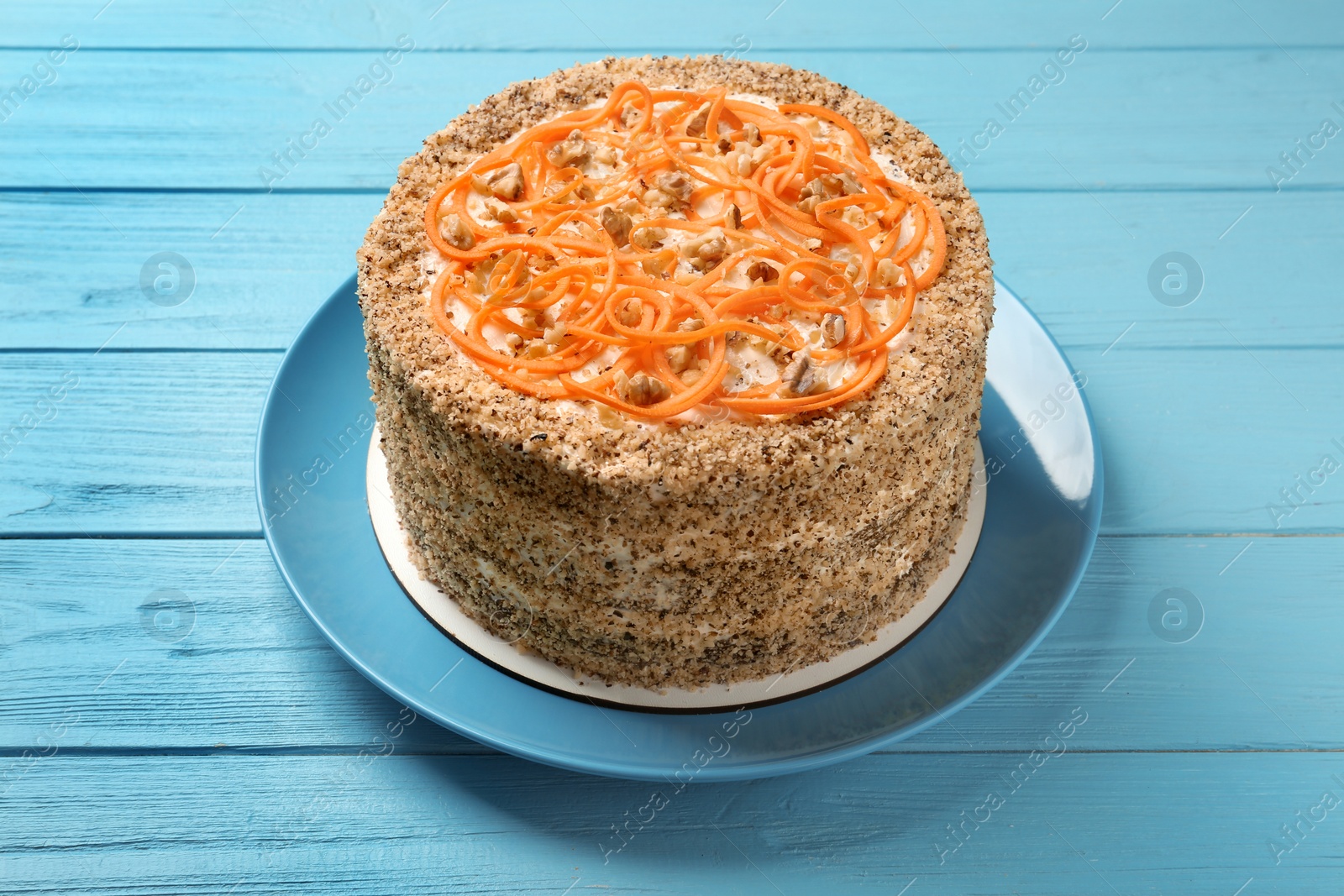 Photo of Dish with delicious carrot cake on blue wooden background