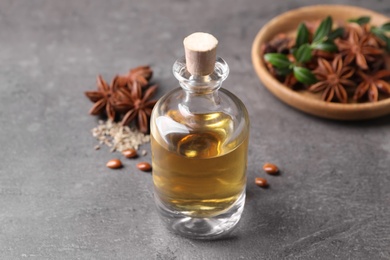 Photo of Anise essential oil and spices on grey table