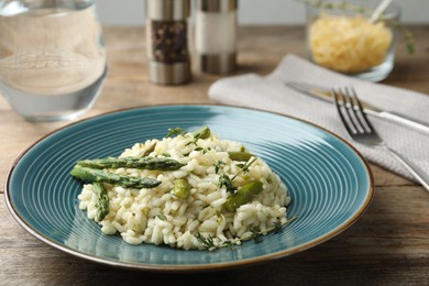Photo of Delicious risotto with asparagus served on wooden table