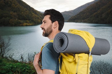 Happy tourist with yellow backpack near lake