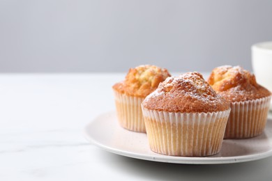 Delicious sweet muffins on white marble table against light grey background, closeup. Space for text