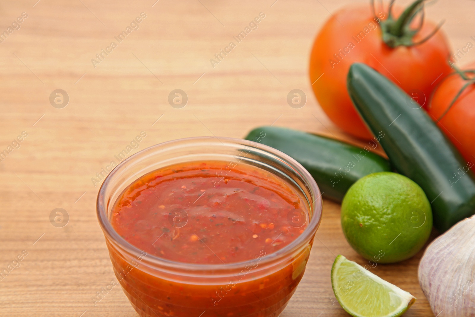 Photo of Tasty salsa sauce and different ingredients on wooden table, closeup. Space for text