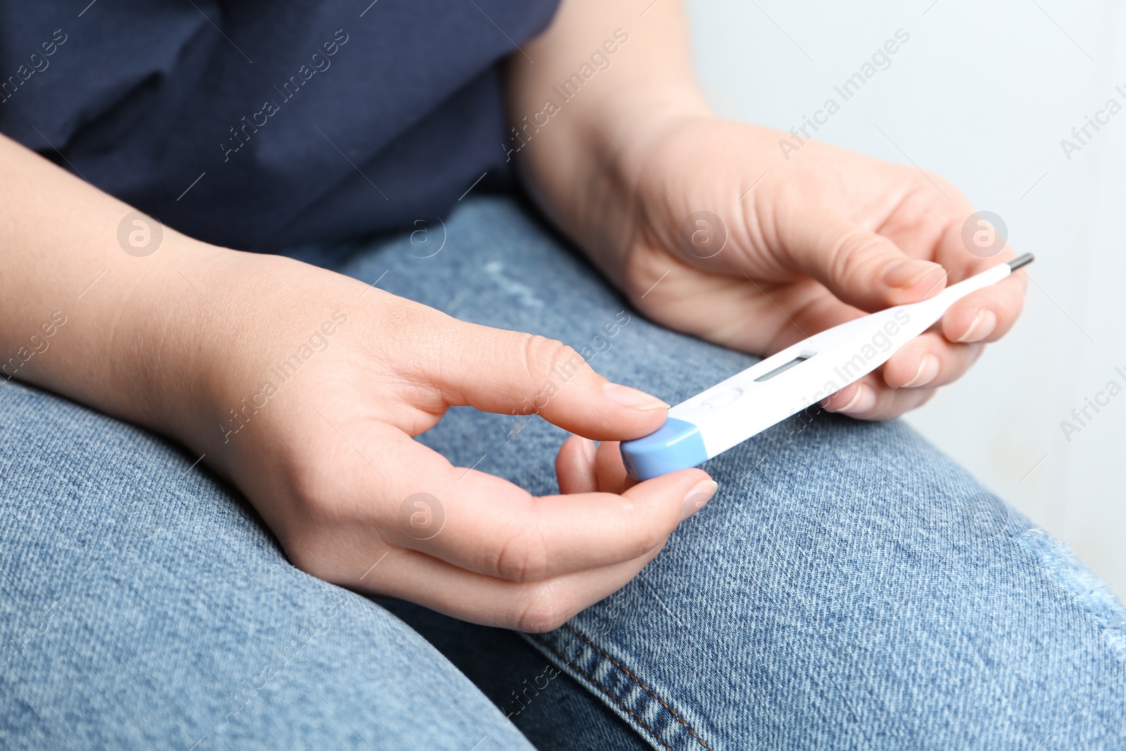 Photo of Woman with digital thermometer on light background, closeup