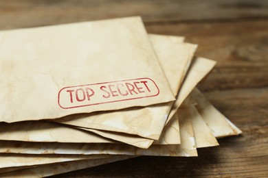 Image of Top Secret stamp. Stacked old letters on wooden table, closeup