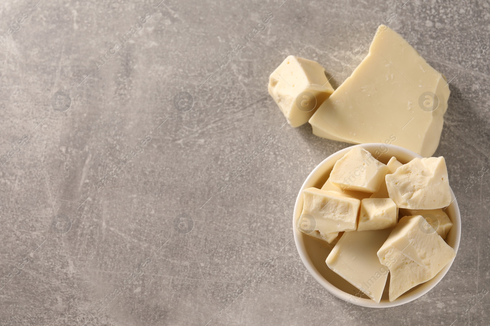 Photo of Pieces of tasty white chocolate on grey table, top view. Space for text