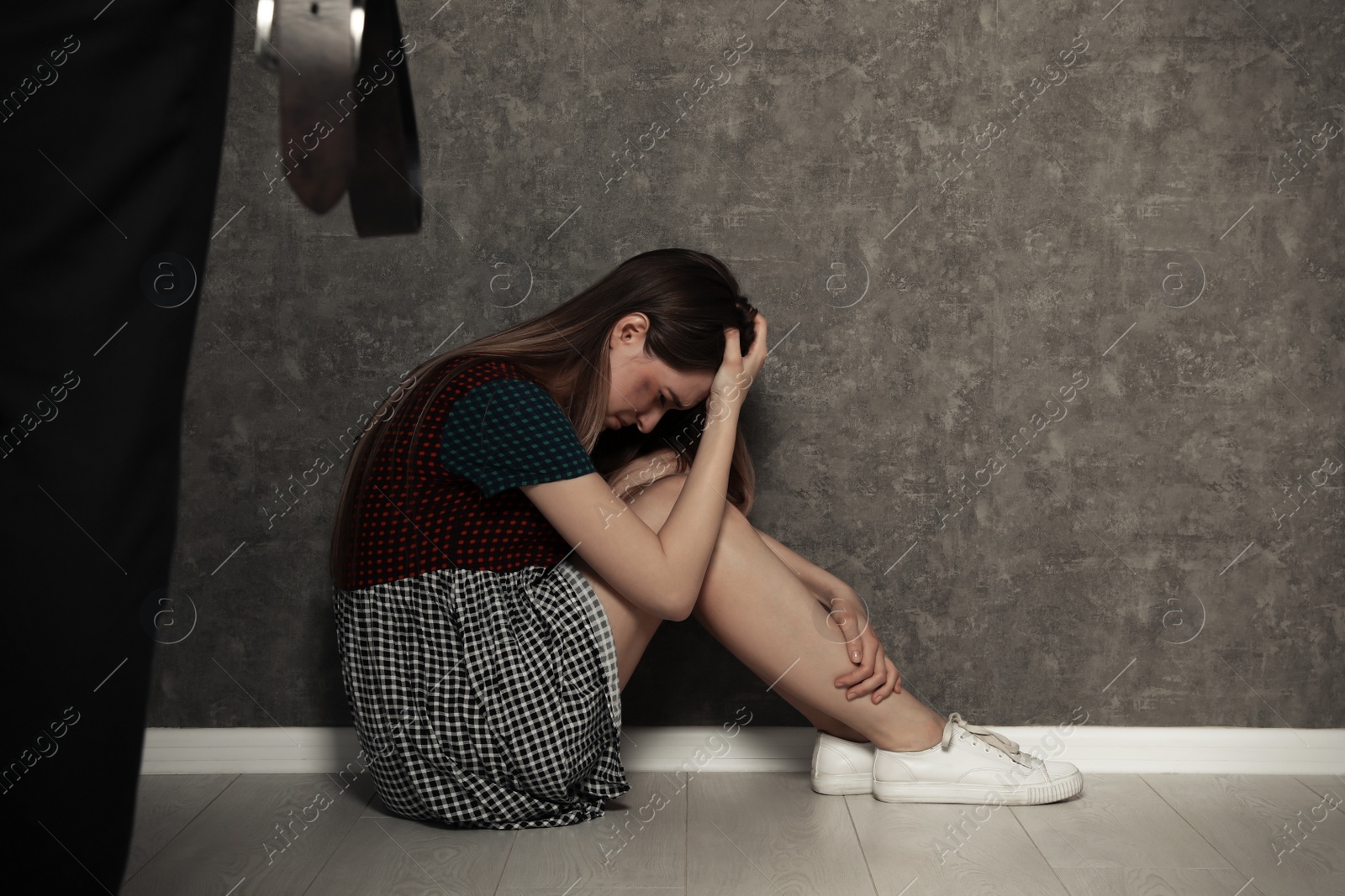 Photo of Man with belt standing in front of crying woman indoors, space for text. Stop sexual assault