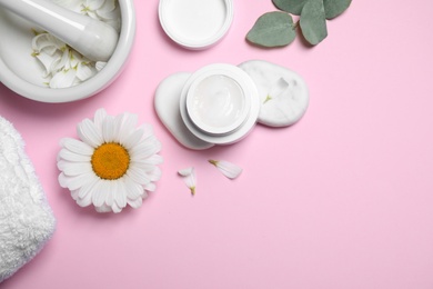 Photo of Flat lay composition with chamomile flower and cream on pink background. Space for text