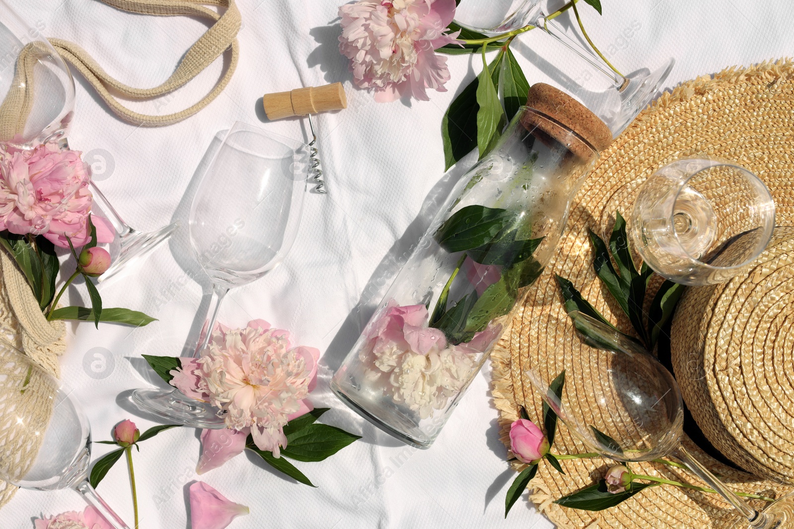 Photo of Flat lay composition with beautiful peonies and wineglasses on white fabric