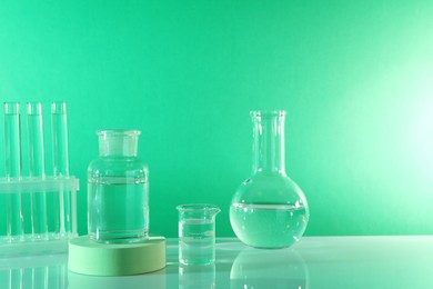Photo of Laboratory analysis. Different glassware on table against green background, space for text