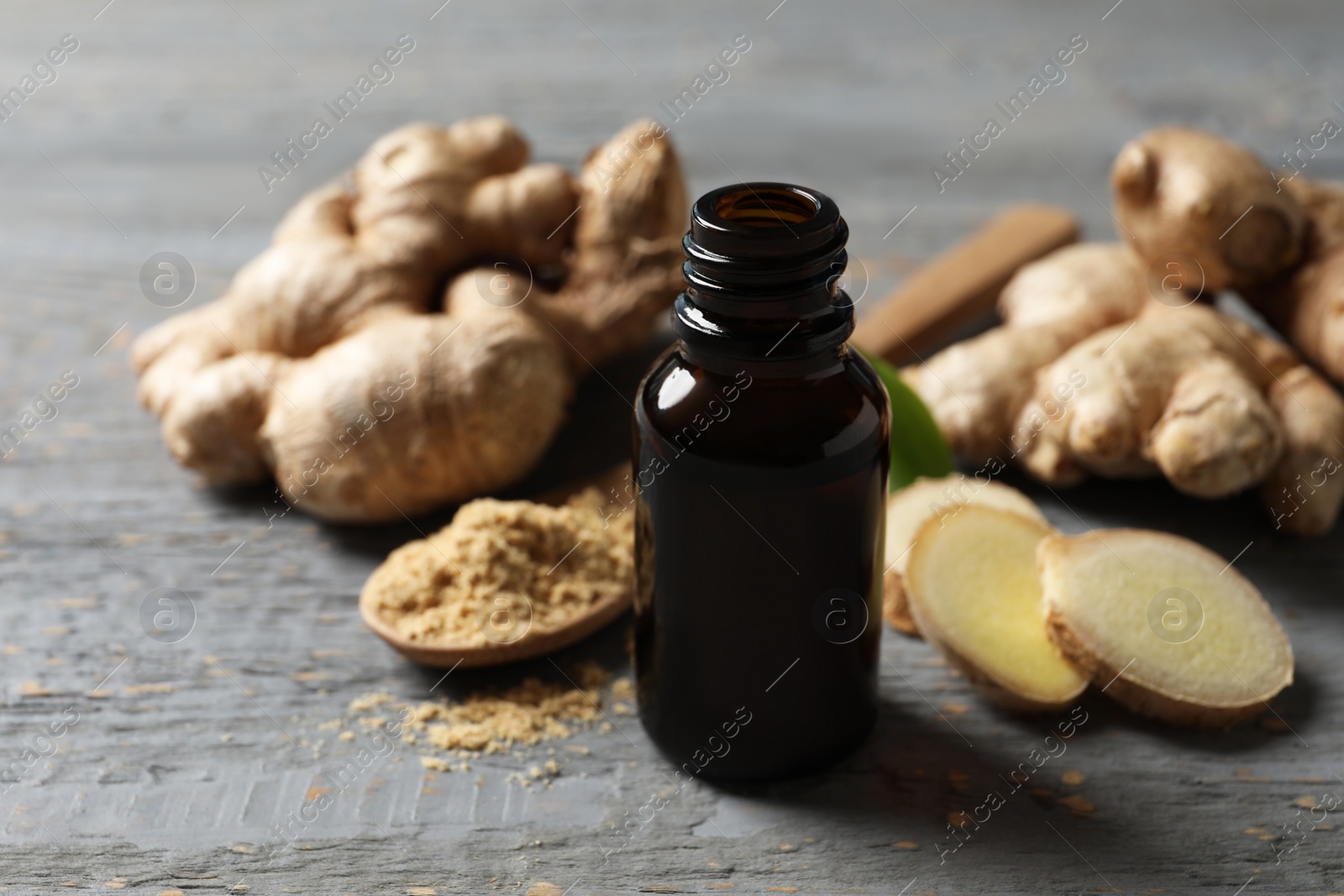 Photo of Ginger essential oil in bottle on light grey table