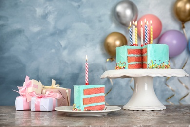 Photo of Fresh delicious cake with candles and gifts on table against color background