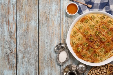 Photo of Delicious sweet baklava served on light blue wooden table, flat lay. Space for text