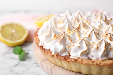 Photo of Serving board with delicious lemon meringue pie on white marble table, closeup