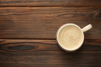 Photo of Cup of coffee on wooden table, top view. Space for text