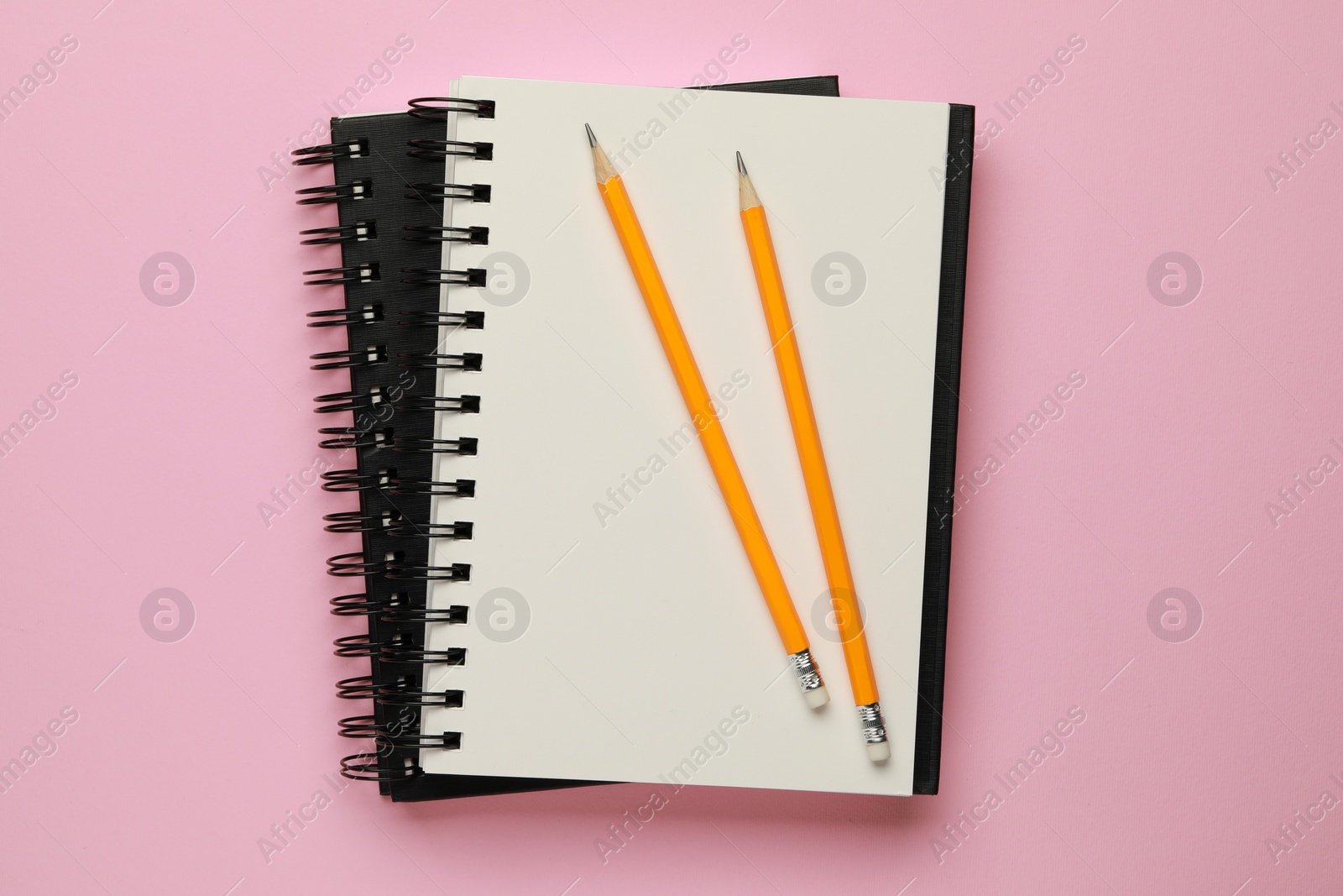 Photo of Notebooks and pencils on pale pink background, top view