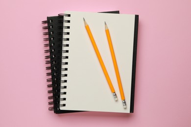 Notebooks and pencils on pale pink background, top view