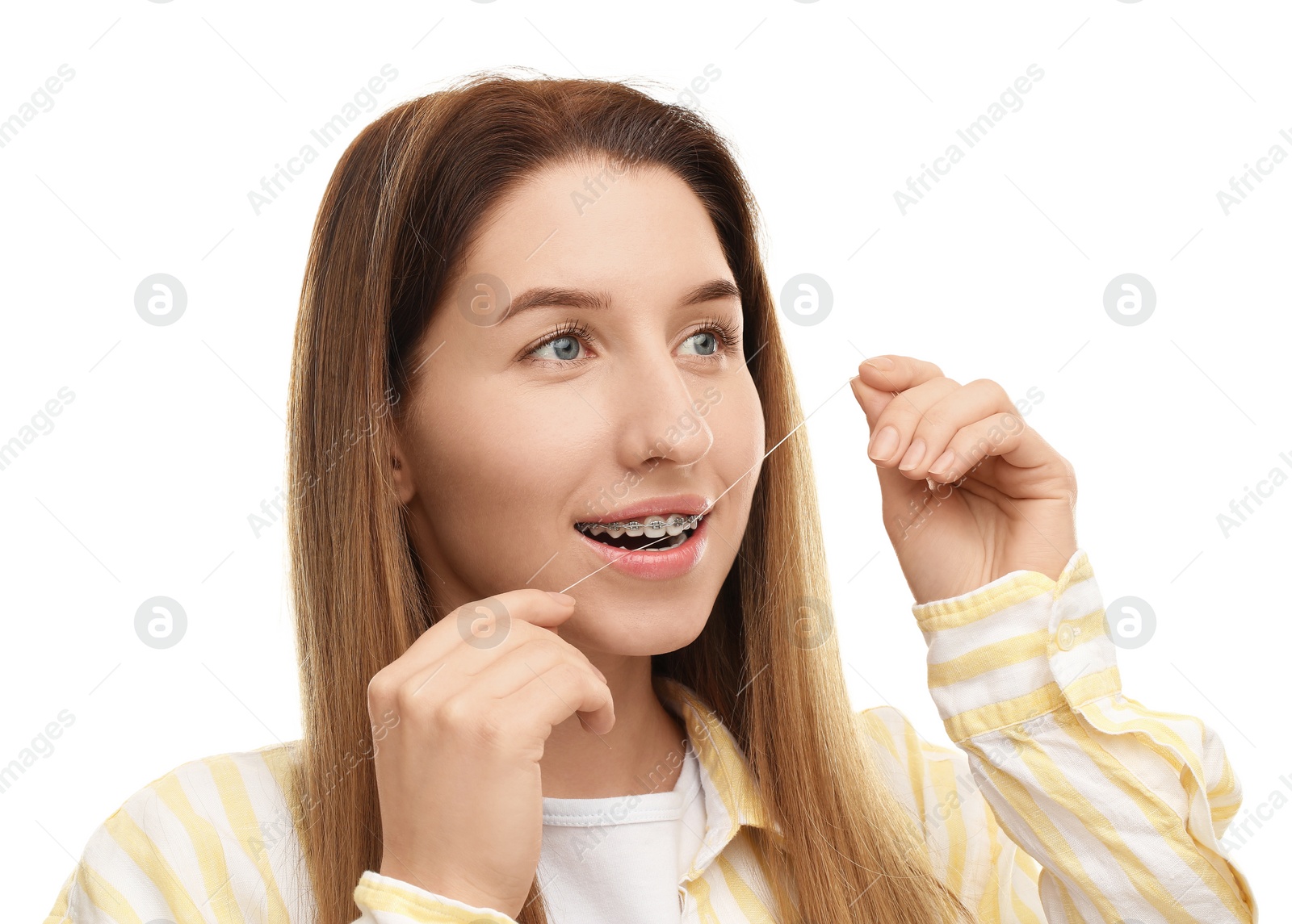 Photo of Smiling woman with braces cleaning teeth using dental floss on white background