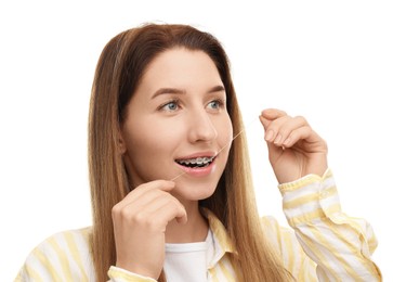 Smiling woman with braces cleaning teeth using dental floss on white background