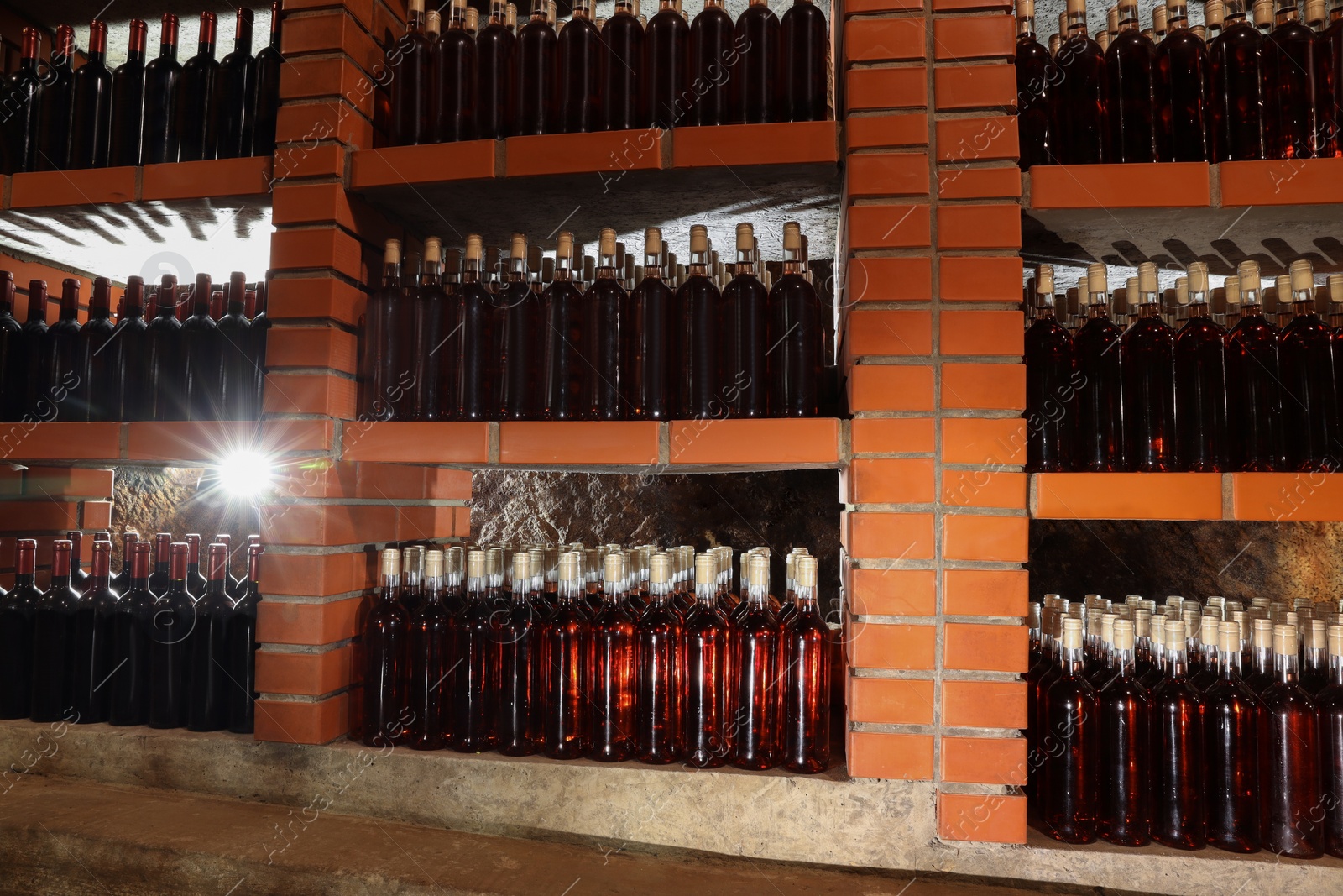 Photo of Many bottles of wine stored on shelves in cellar