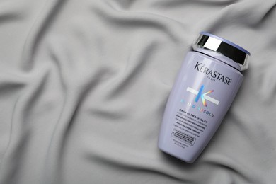 MYKOLAIV, UKRAINE - SEPTEMBER 07, 2021: Kerastase shampoo on grey fabric, top view. Space for text