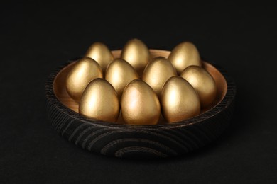 Photo of Many shiny golden eggs on black background