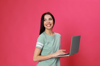 Photo of Young woman with modern laptop on pink background