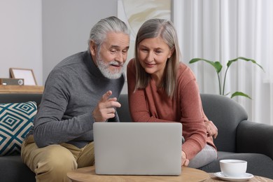 Elderly couple with laptop discussing pension plan in room