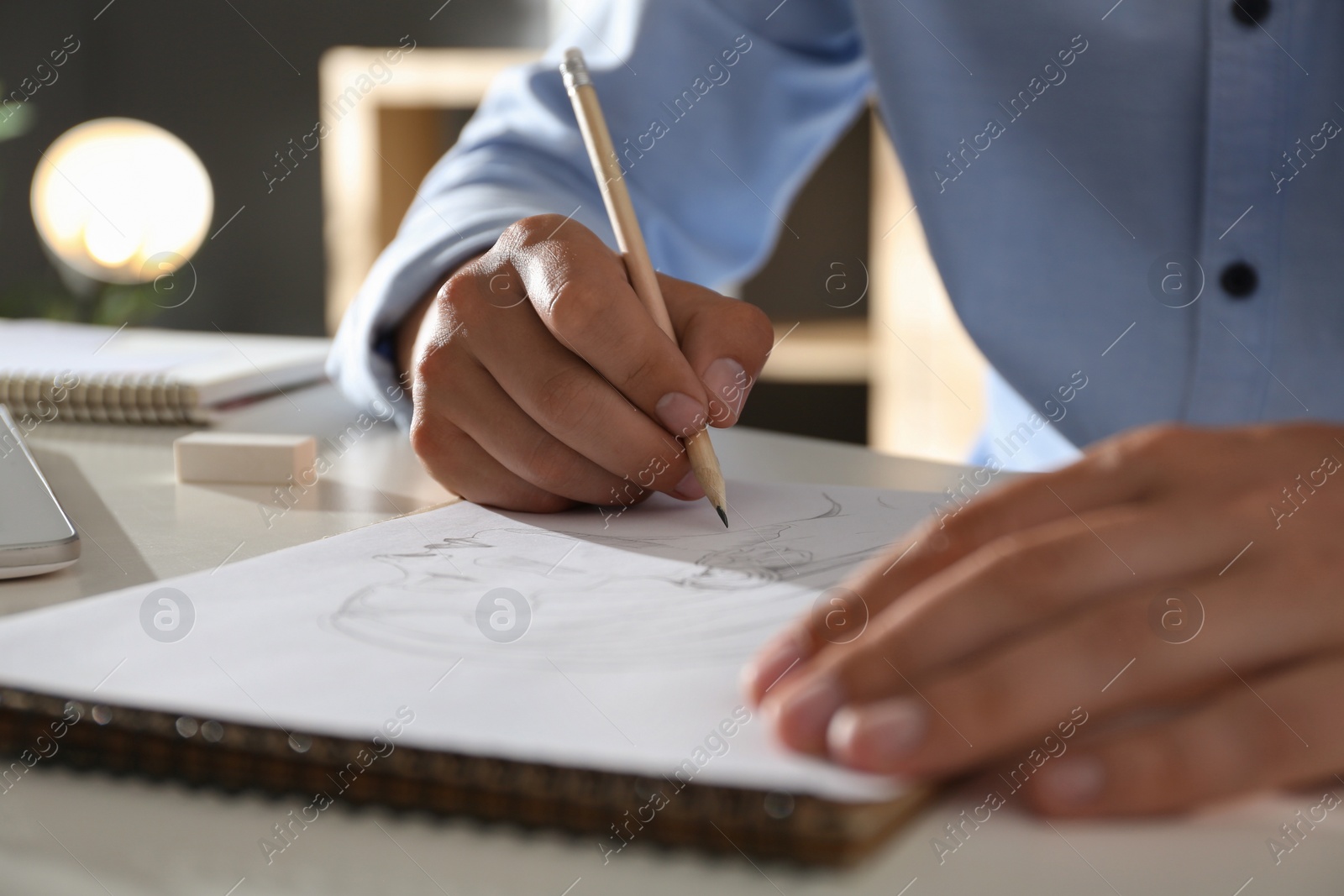 Photo of Man drawing portrait with pencil in notepad at table, closeup