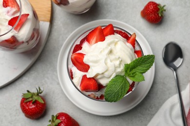 Photo of Delicious strawberries with whipped cream served on light grey table, flat lay