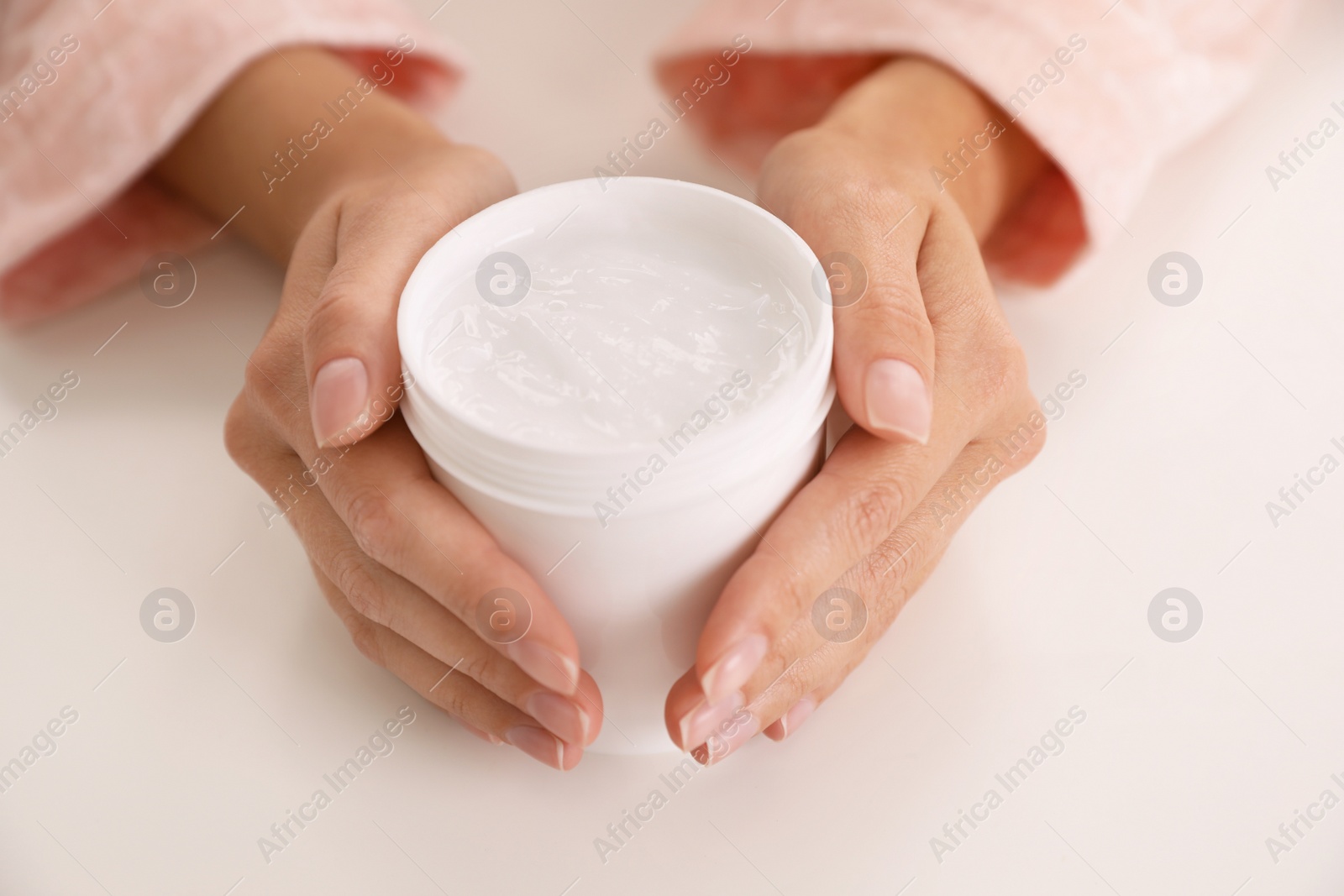 Photo of Woman with jar of moisturizing cream at white table, closeup