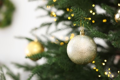 Photo of Christmas ball hanging on fir tree branch indoors, closeup. Space for text