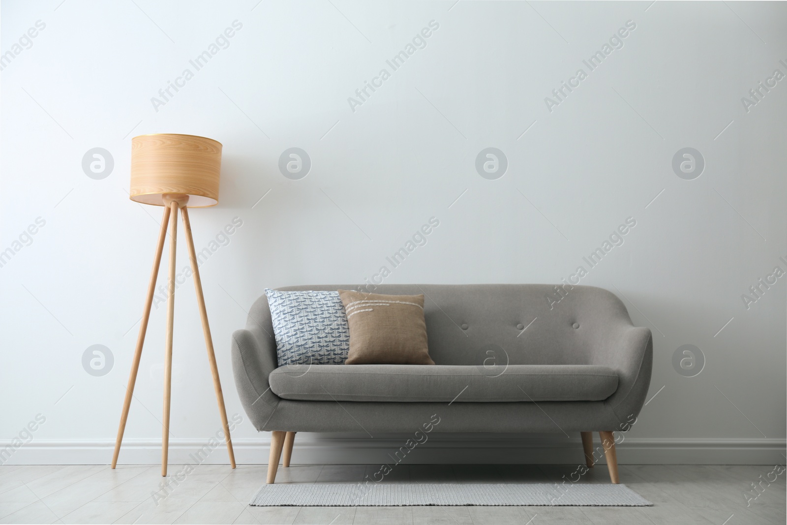 Photo of Grey sofa with pillows near white wall in stylish living room interior