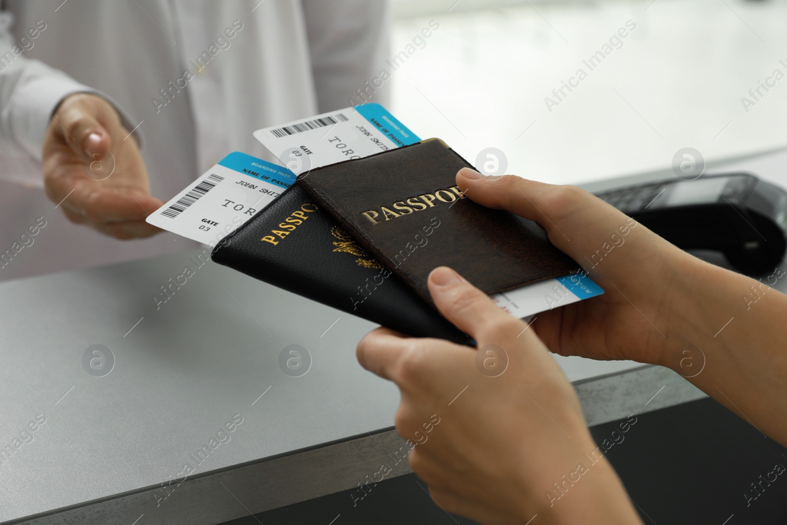 Photo of Agent giving passports and tickets to man at check-in desk in airport, closeup