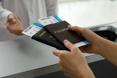 Agent giving passports and tickets to man at check-in desk in airport, closeup